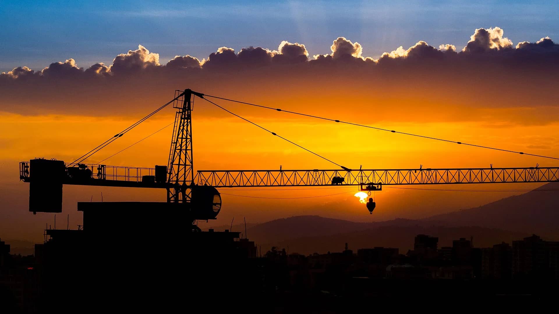 A construction crane silhouetted against an orange sunset over Addis Ababa