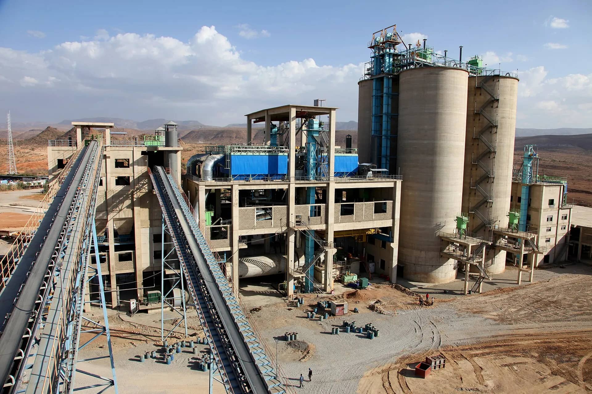 A cement plant with conveyor belts and silos under a blue sky
